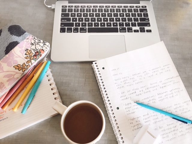 Coffee, notebook, computer, and pens